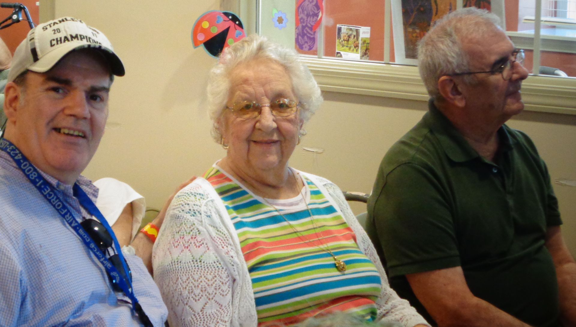 Two men and an elderly woman are sitting next to each other in a room.