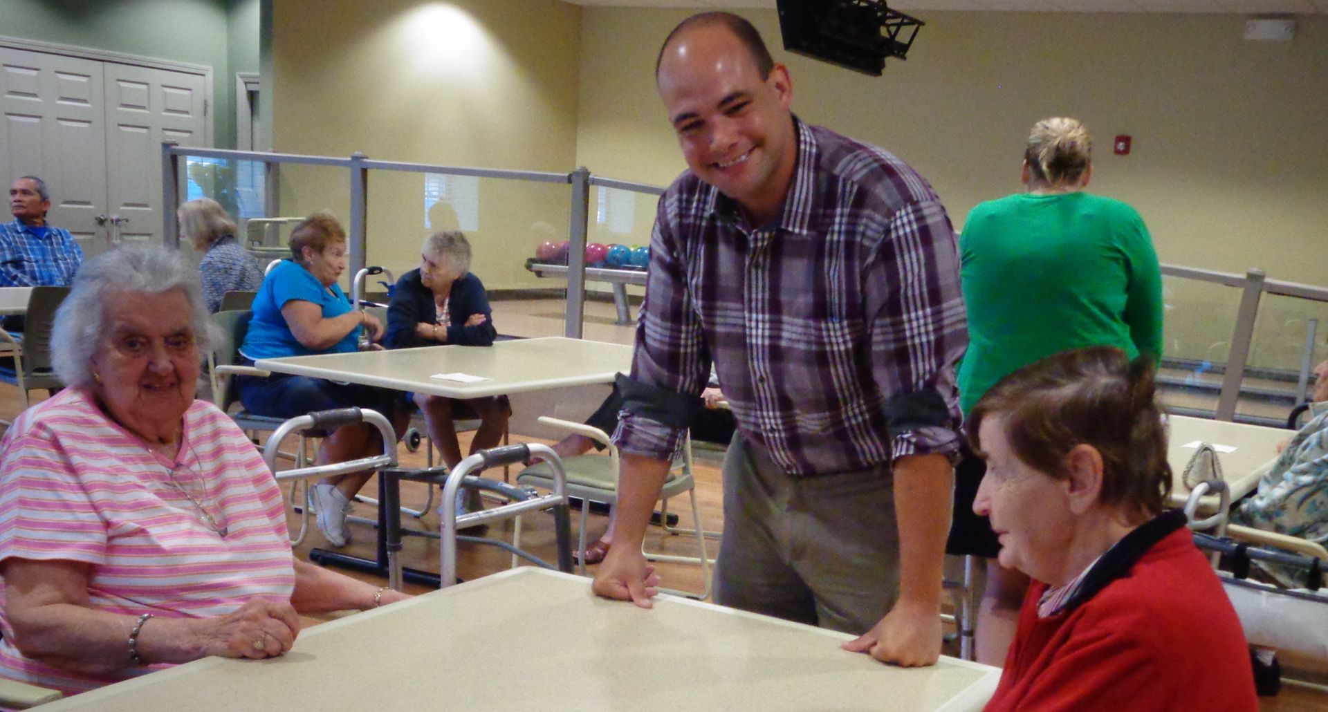 A man is standing next to a woman at a table in a nursing home.