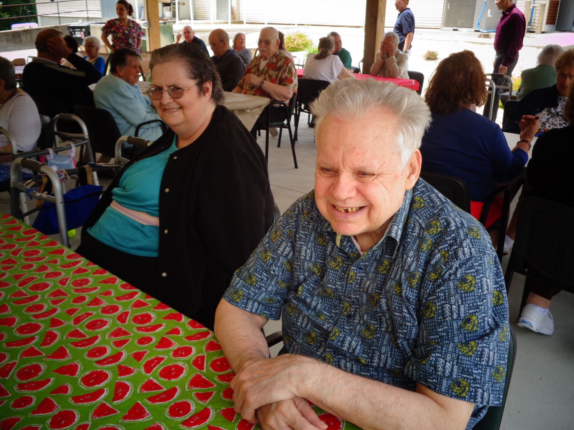 A man and a woman are sitting at a table with a watermelon tablecloth
