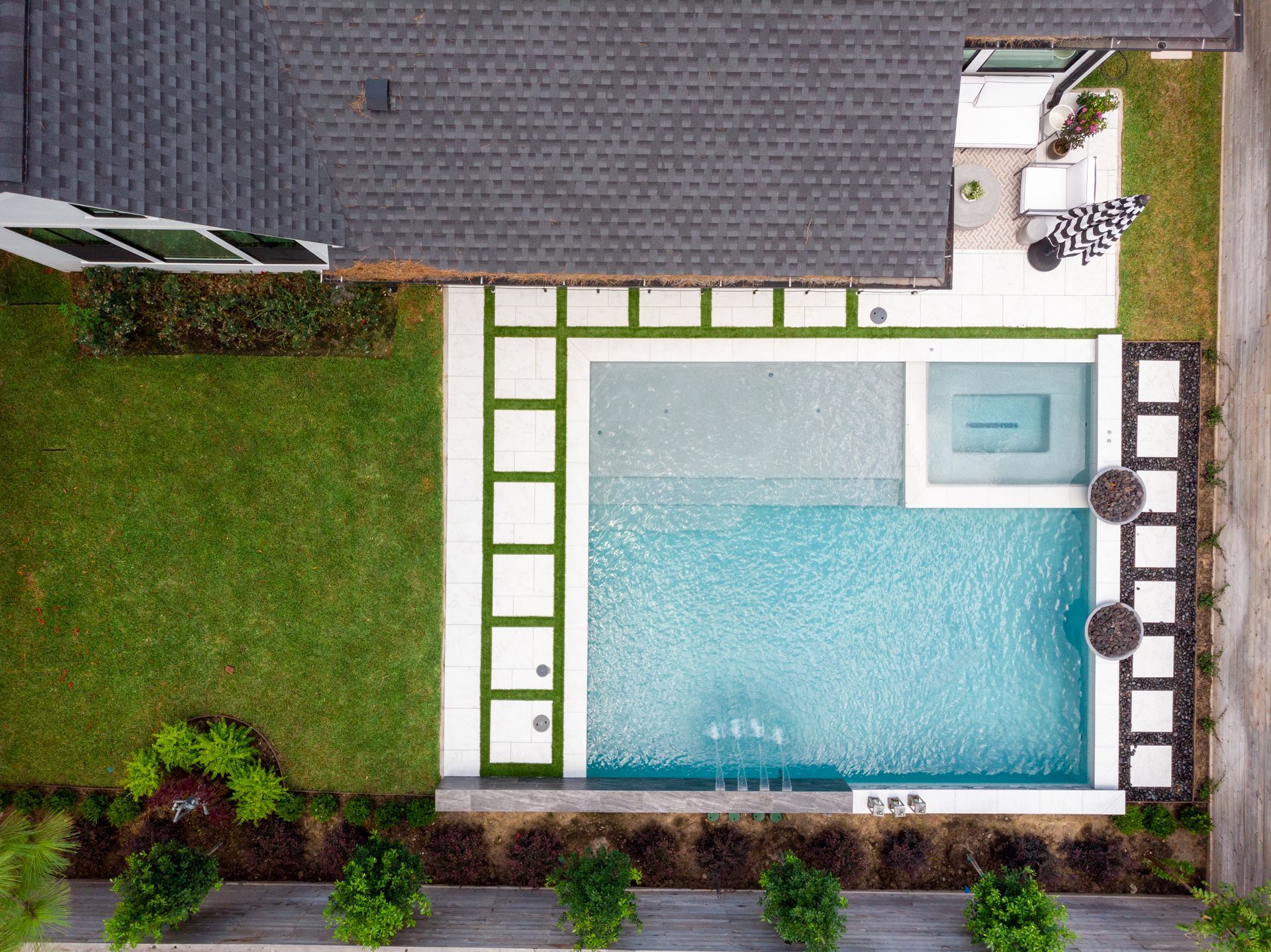 Modern backyard pool with teal loungers, stone deck, and sunset sky reflections