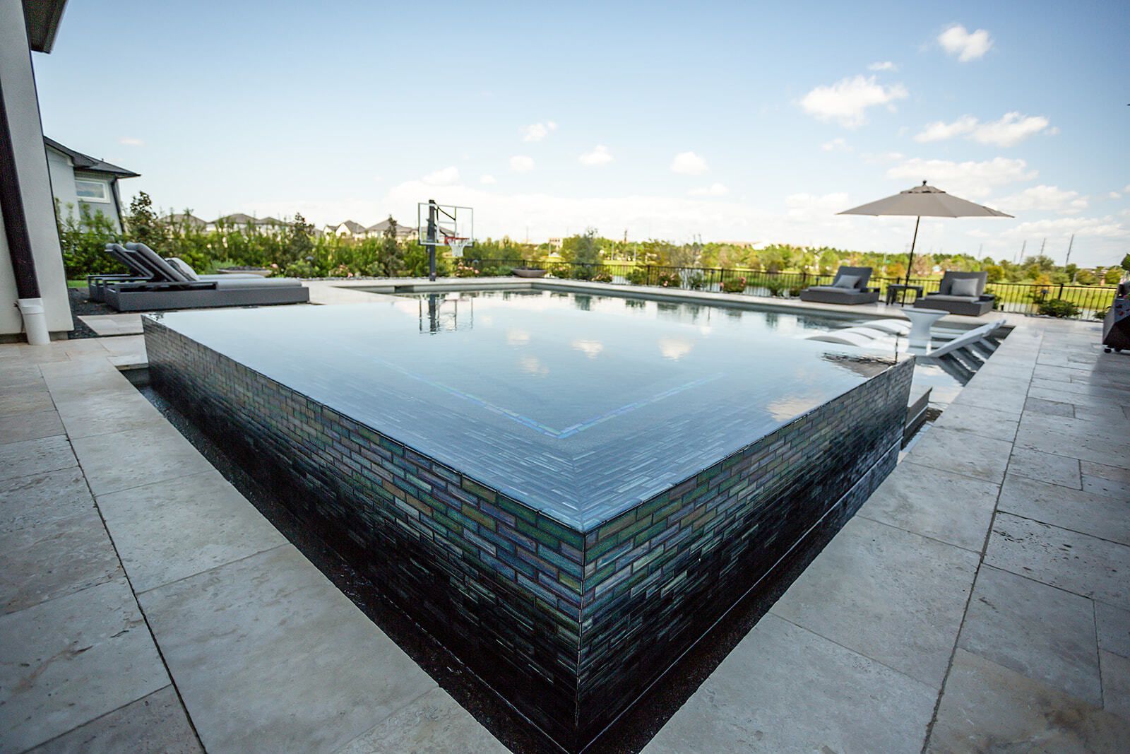 Modern backyard pool with built-in seating and lounge chairs at sunset