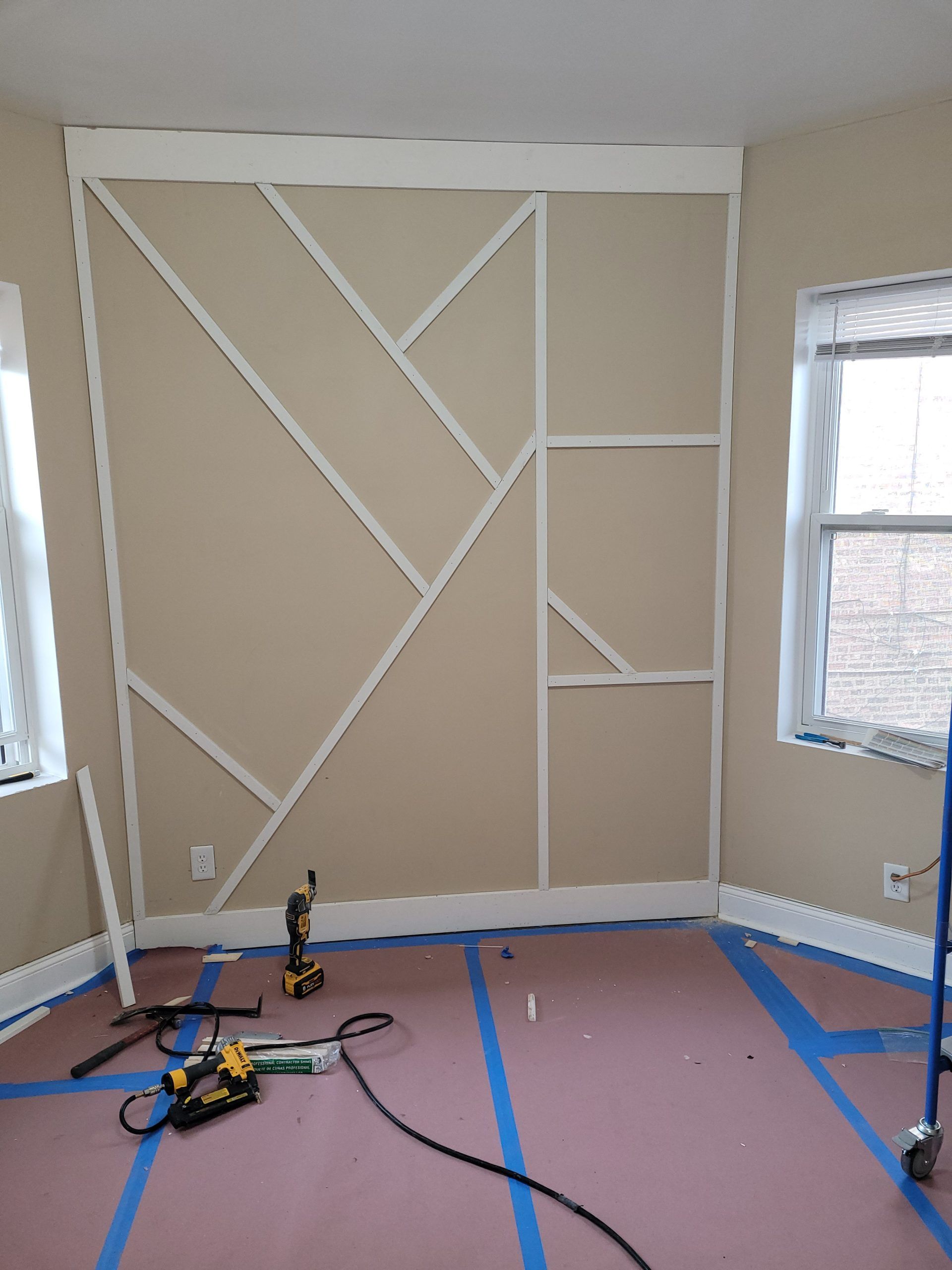 Room with geometric wall trim under construction; tools on the floor.