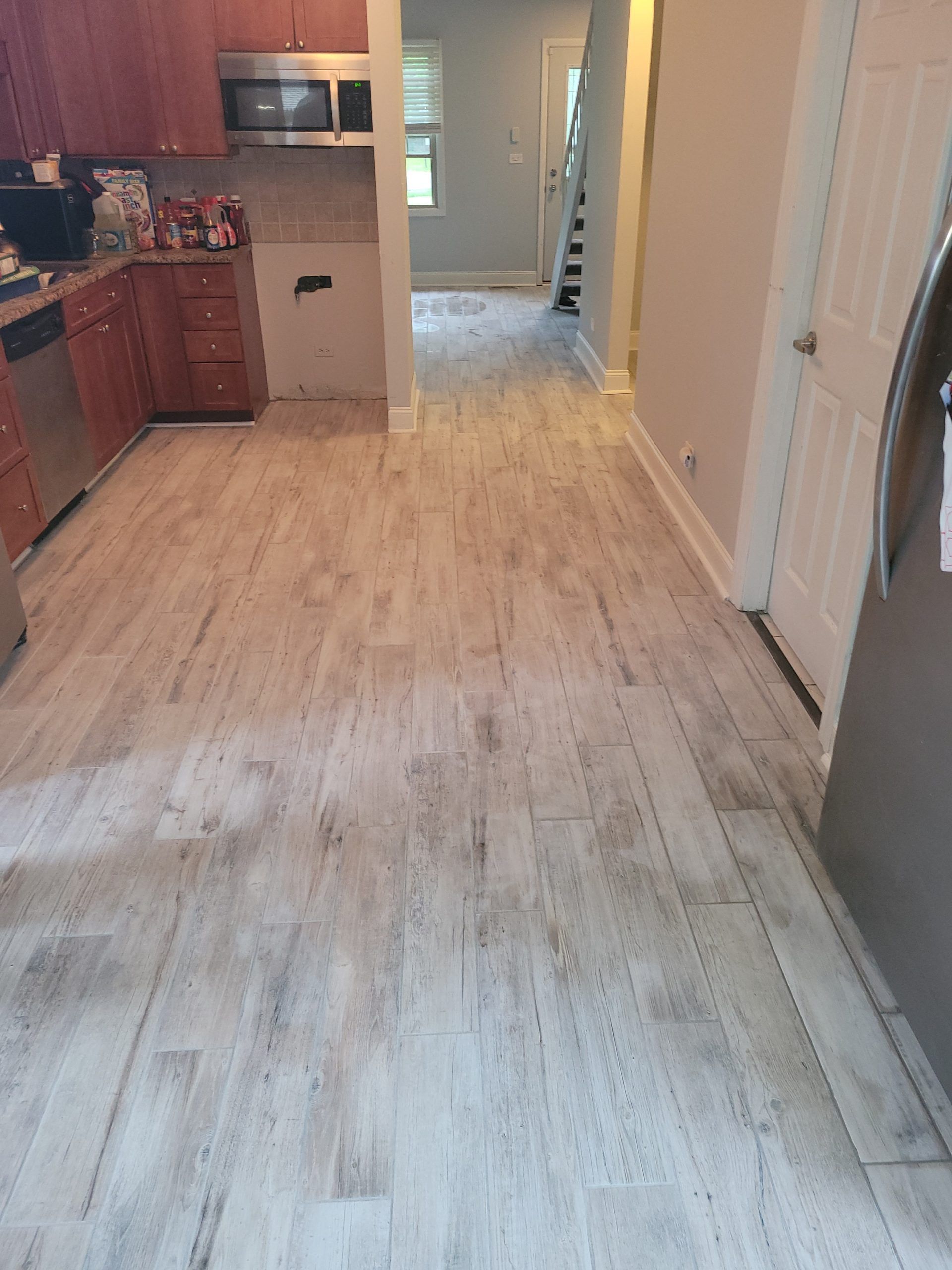 Kitchen with light-colored, wood-look flooring. Dark brown cabinets and stainless steel appliances are visible.