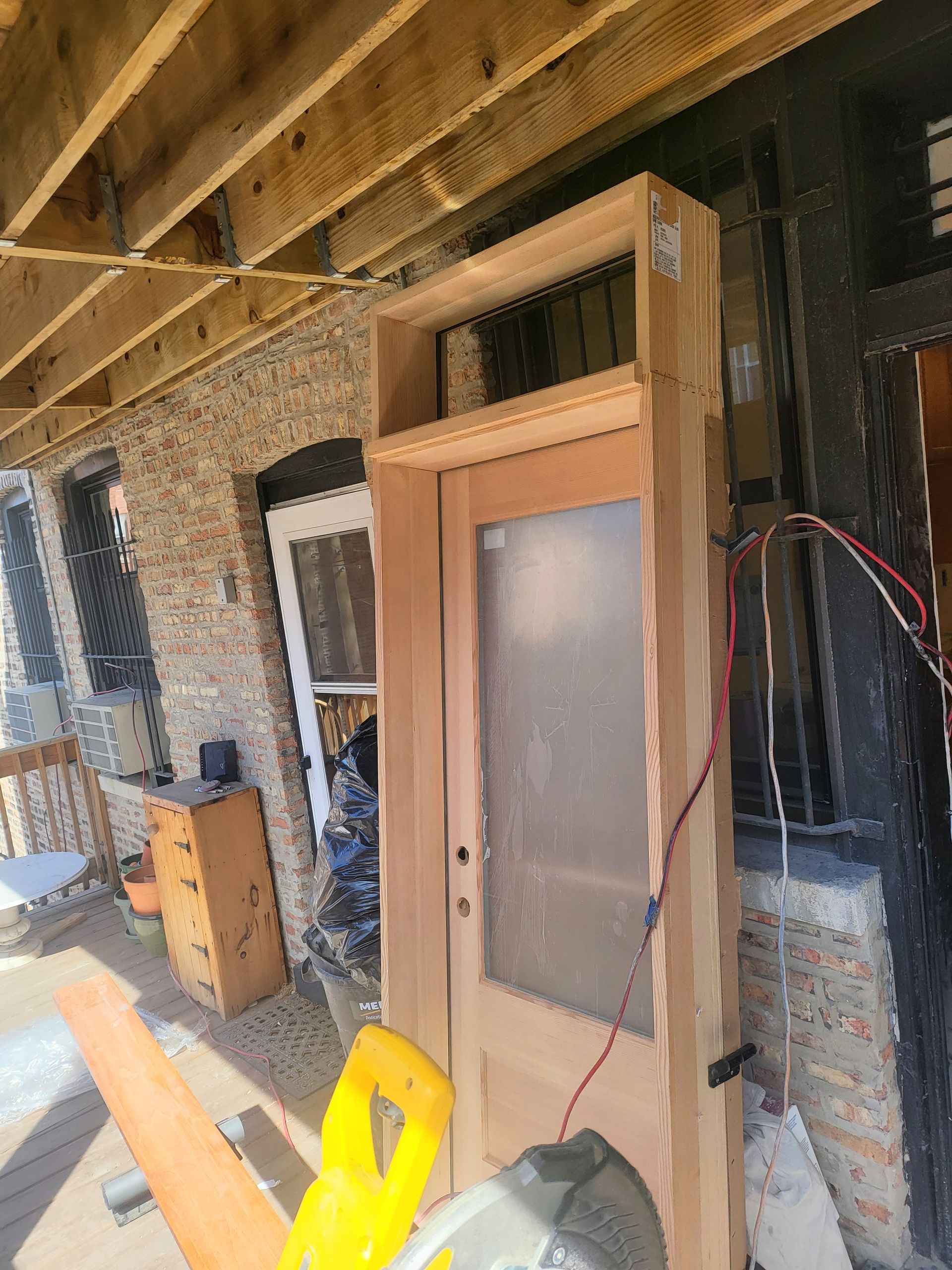 Two construction workers in a room with drywall, one applying material to the wall and the other inspecting a window.