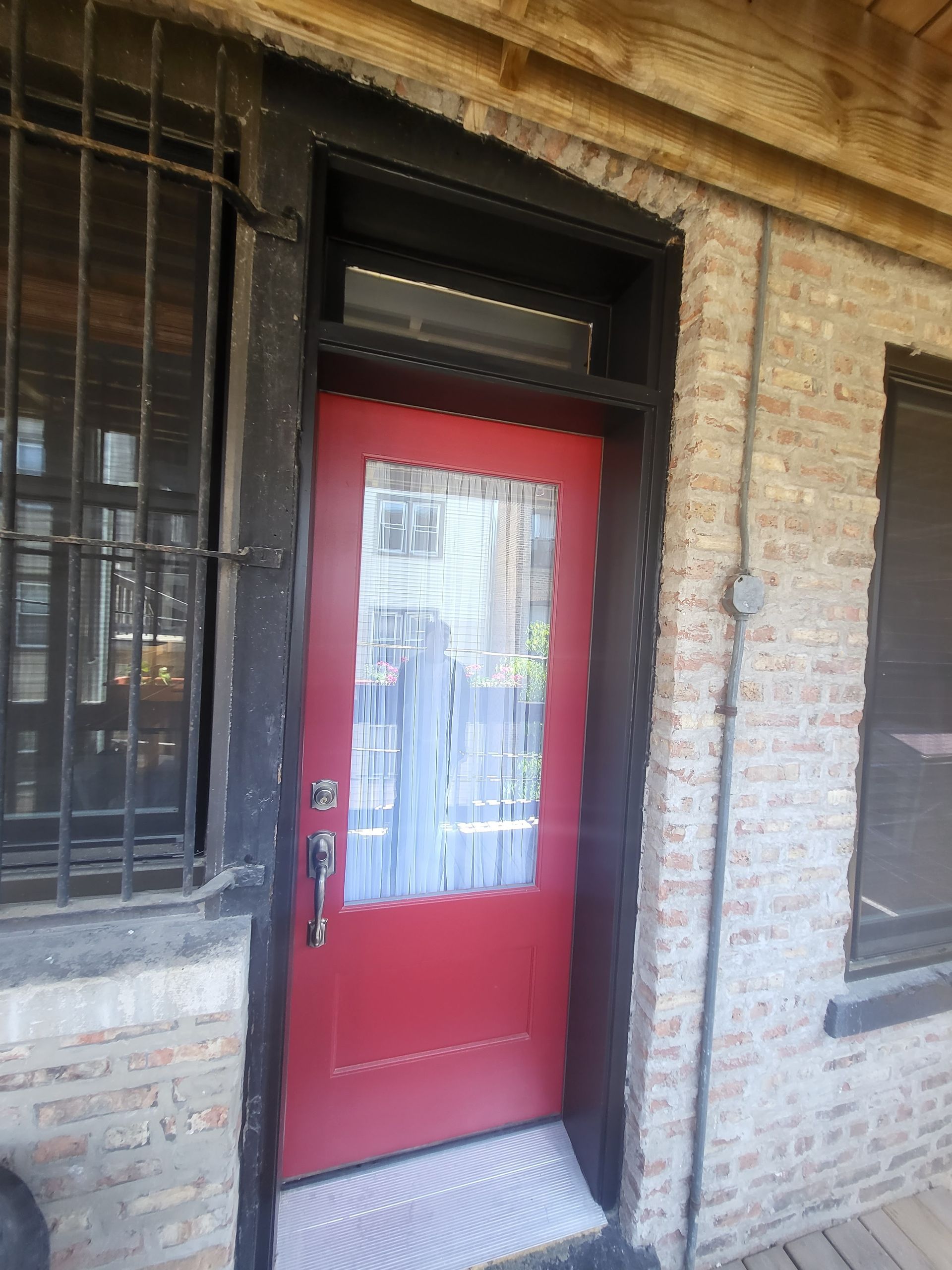 Red door with glass panel, brick building exterior.