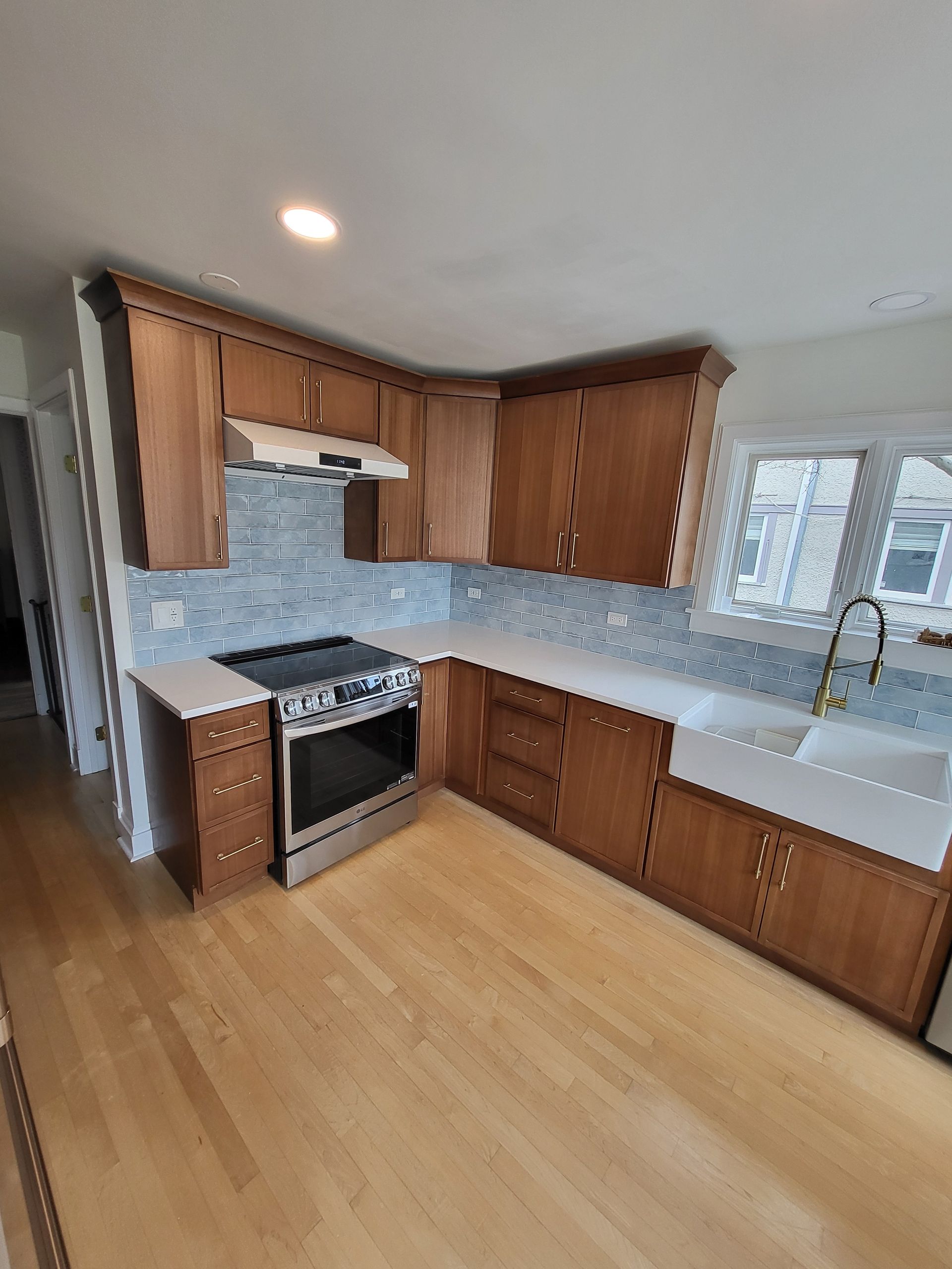 Gray-tiled shower with gold fixtures, glass door, and a white, angular ledge.