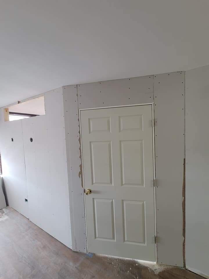 Interior view of a door set in a drywall wall, under construction. White door, gray drywall.