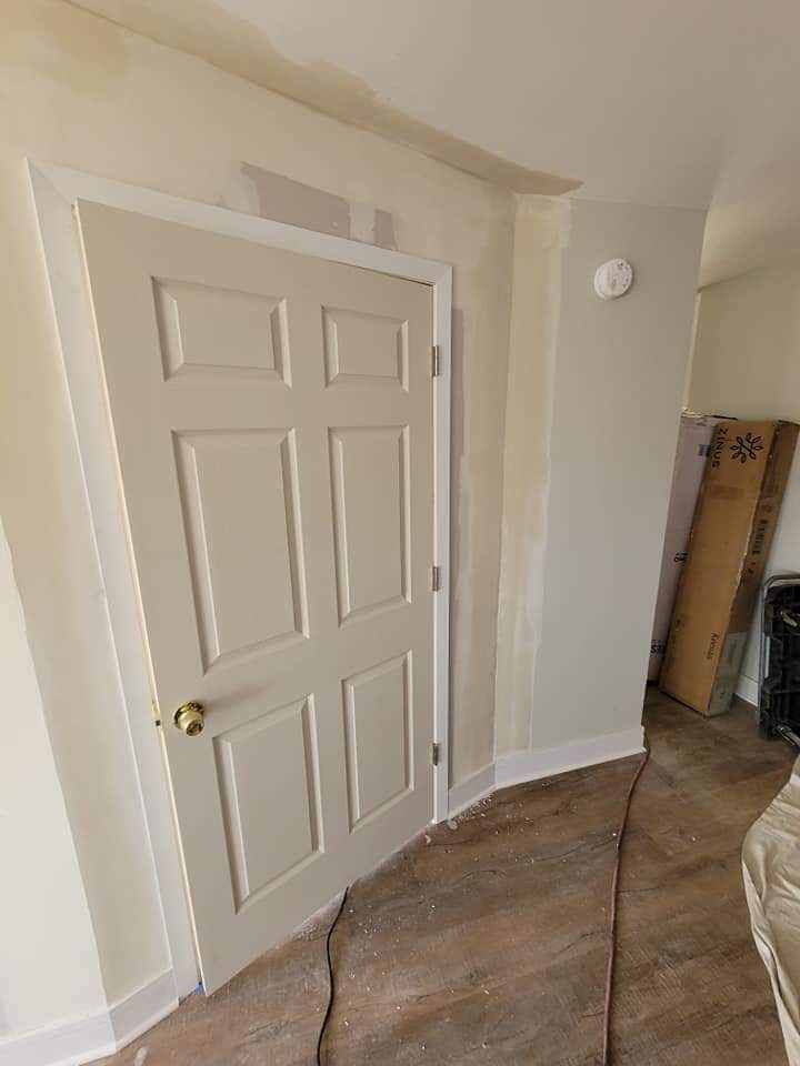 A closed, beige six-panel door with white trim, set in a light-colored doorway.
