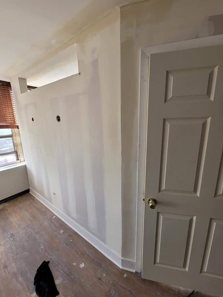 Room with drywall on walls, door, window with blinds, and wood-look flooring.