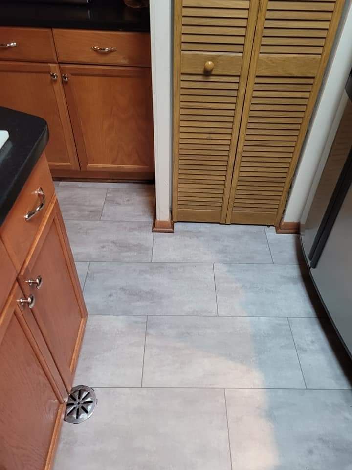 Kitchen floor with light gray tile. Brown cabinets and a pantry door are visible.