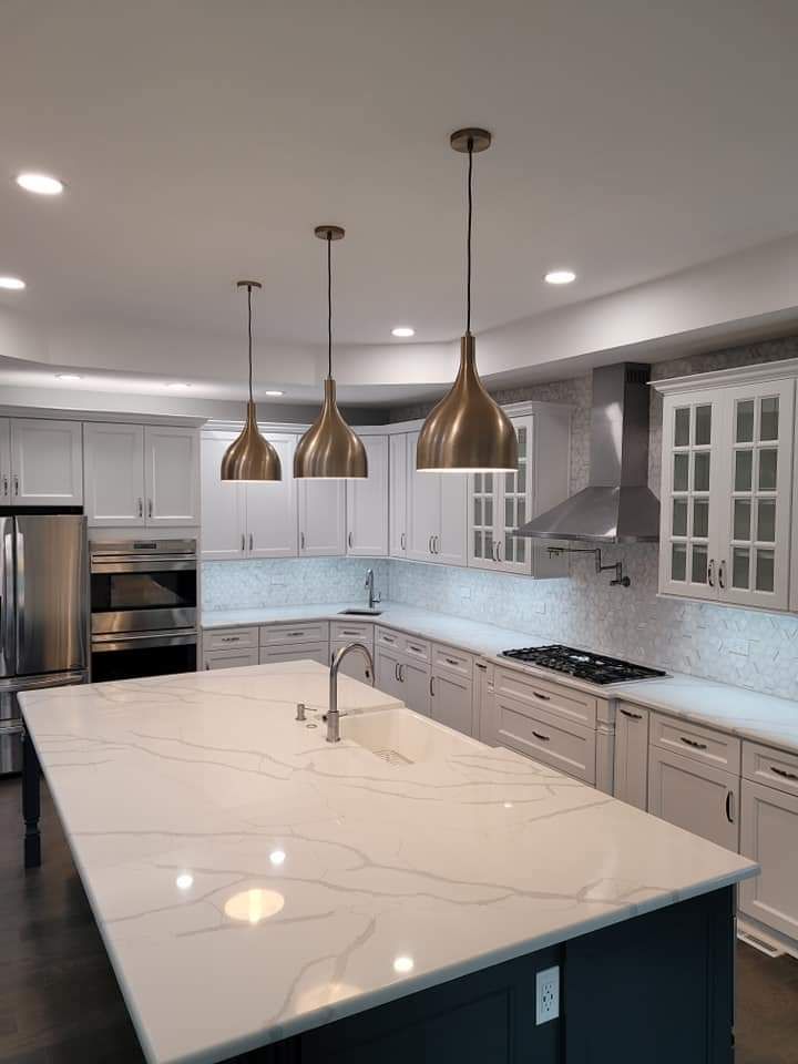 Modern kitchen with a white countertop island, three pendant lights, and white cabinetry.