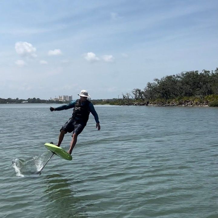 A man is flying a foil board in the water.