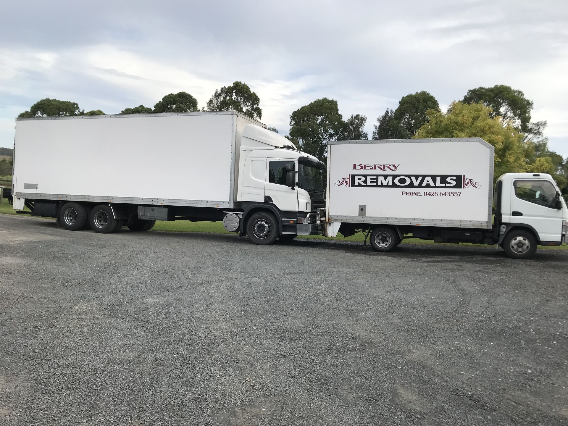 A white moving truck is parked in front of a brick house