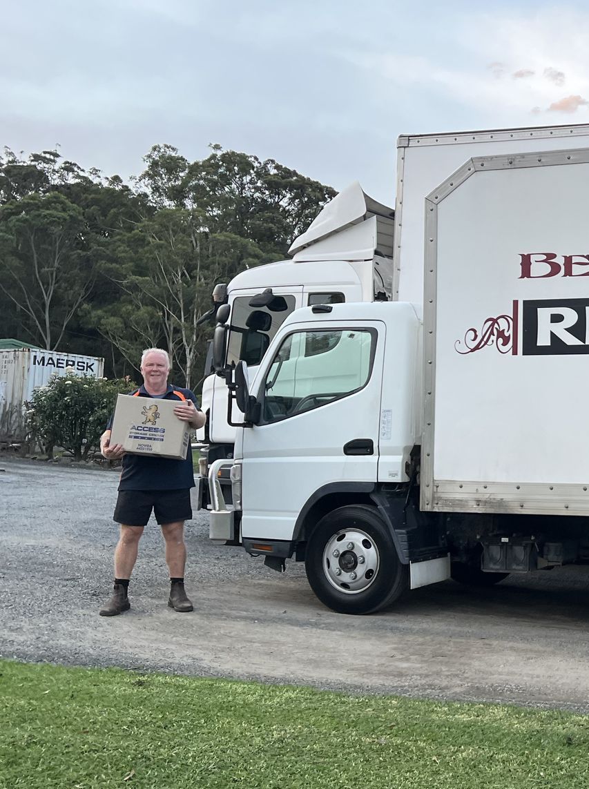 Two men are carrying boxes on a dolly in a living room.