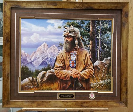 A framed painting of a man with a beard in front of mountains