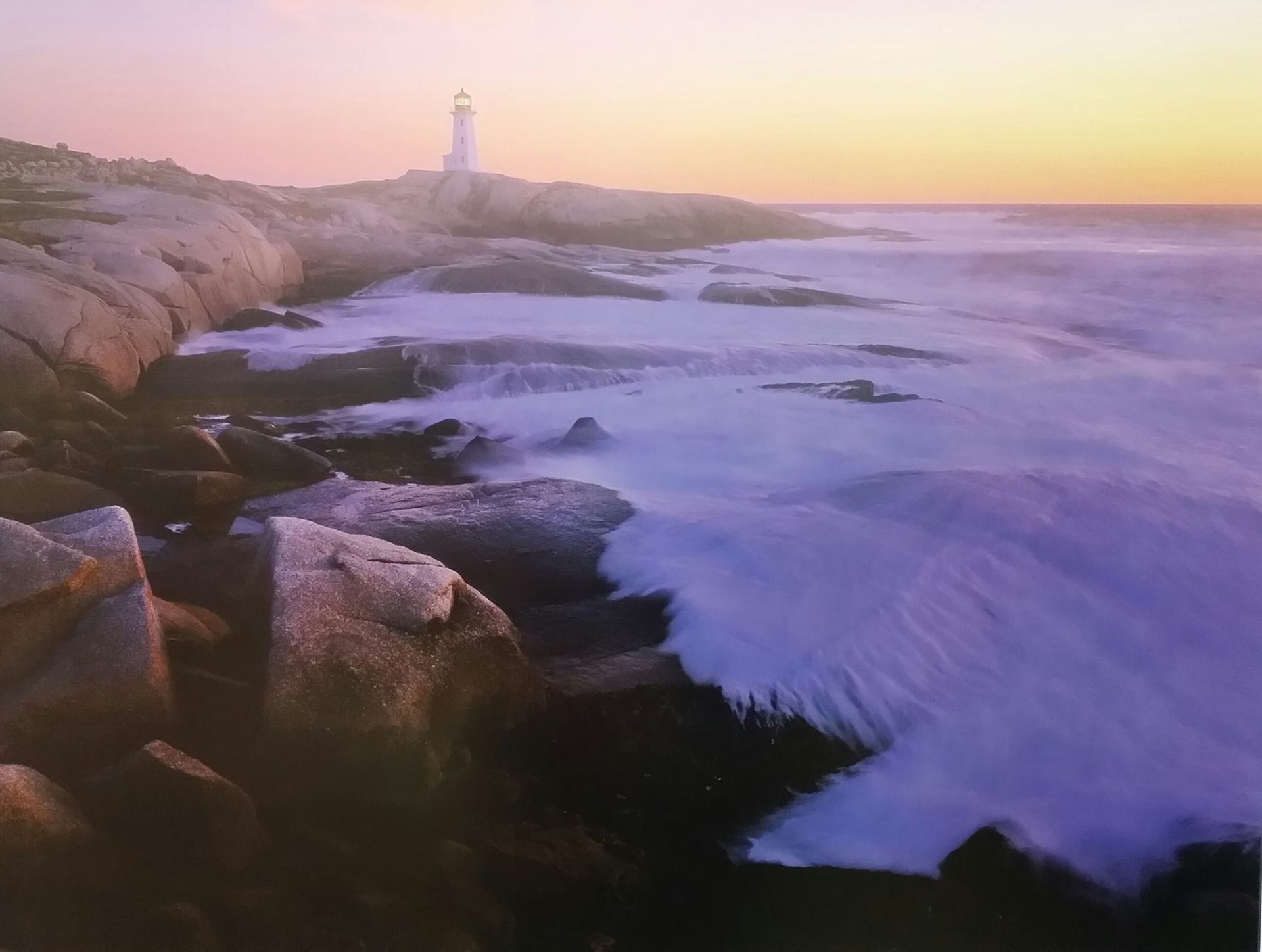 A lighthouse sits on a rocky cliff overlooking the ocean