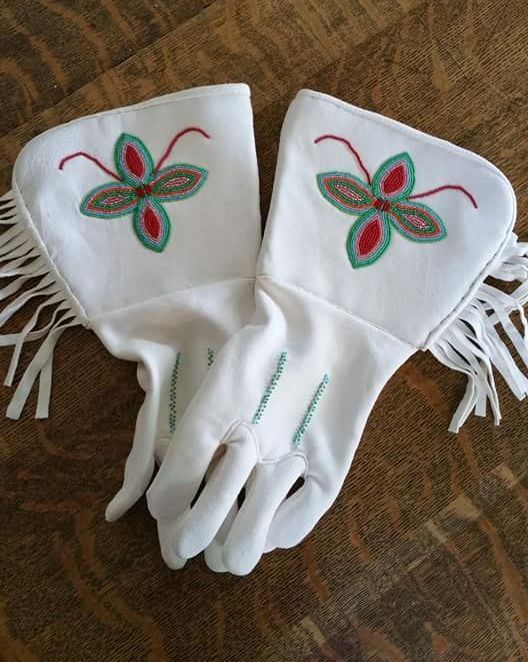 A pair of white gloves with green and red flowers on them