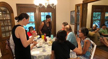 A group of people are sitting around a table in a living room.