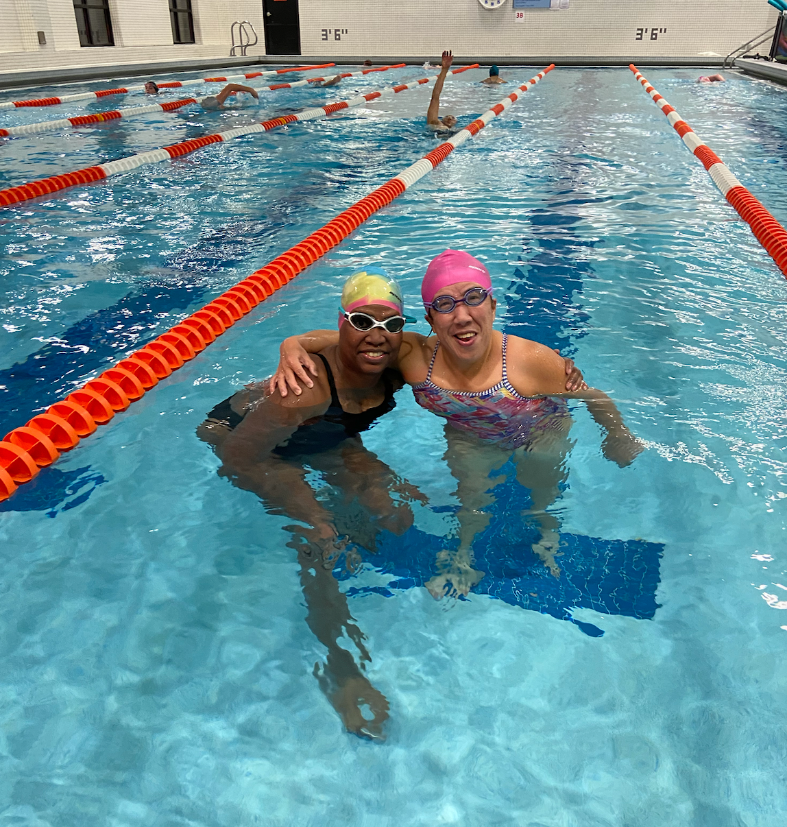 Two women are posing for a picture in a swimming pool.