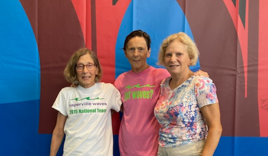 Three people are posing for a picture in front of a colorful wall.