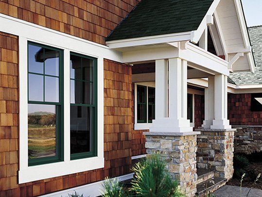 The front of a house with green windows and a stone porch.