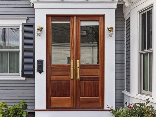 The front door of a house with two wooden doors and a mailbox.