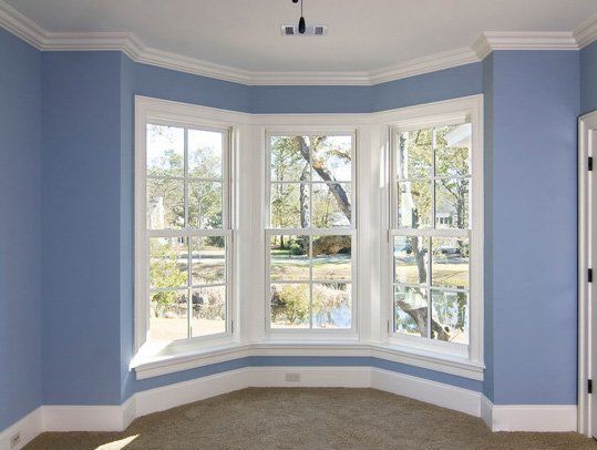 An empty room with blue walls and a bay window