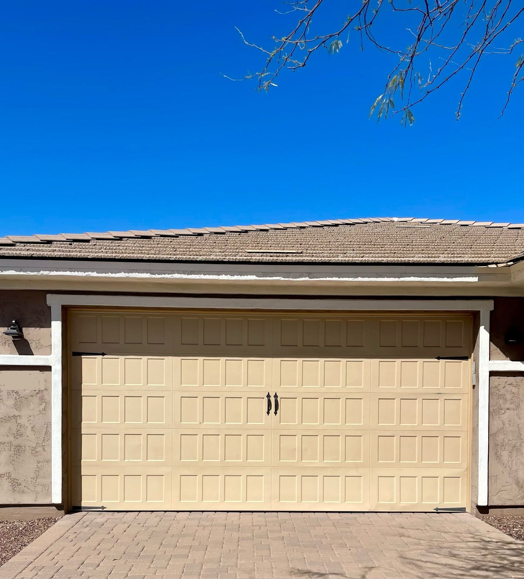 A tan garage door with a blue sky in the background