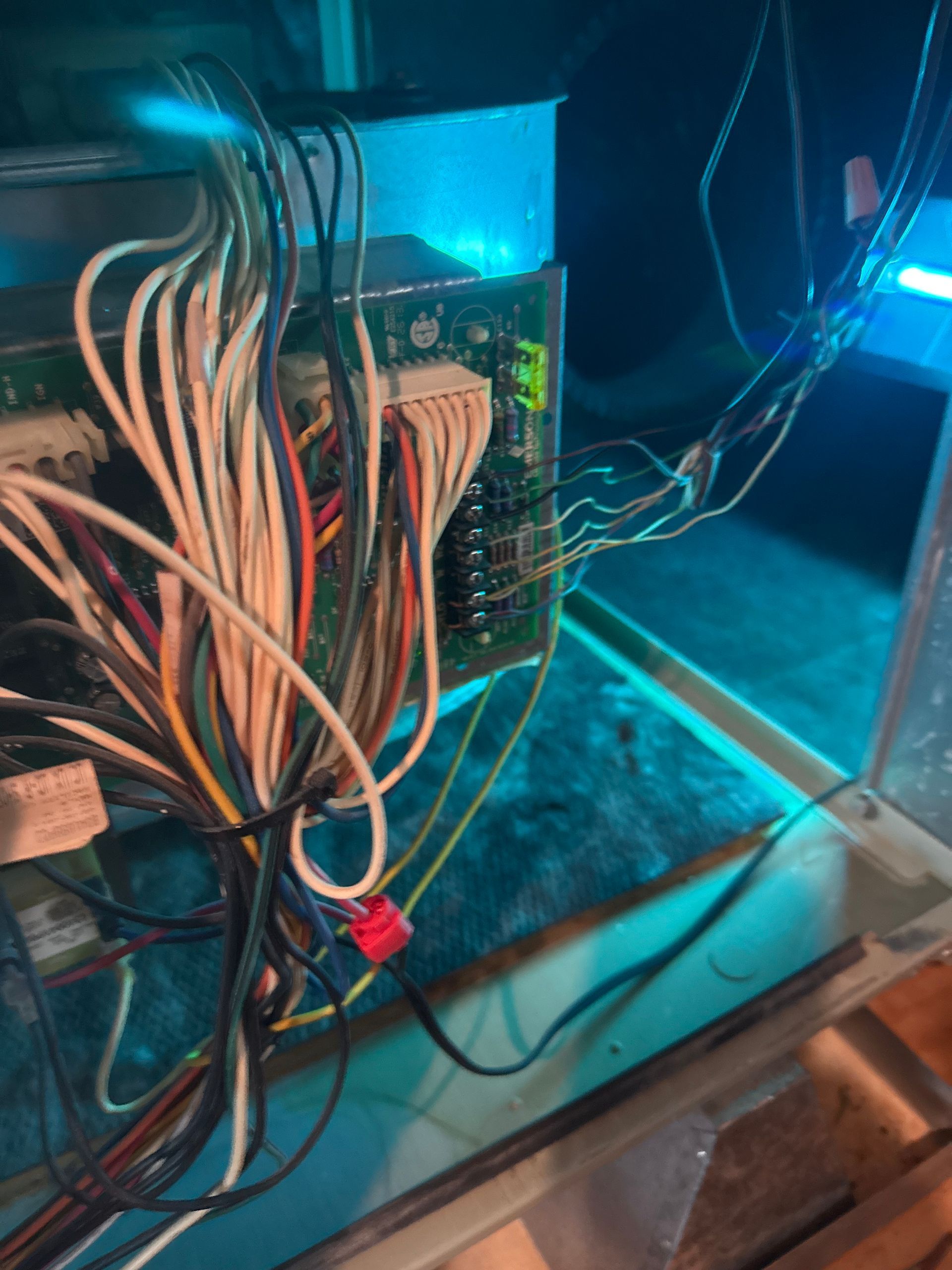 Wiring and circuit boards inside a blue-lit electronics enclosure with tangled cables