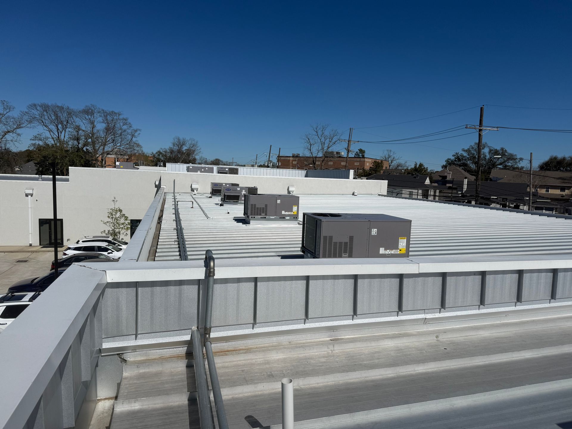 Flat rooftop with HVAC units and vents under a clear blue sky