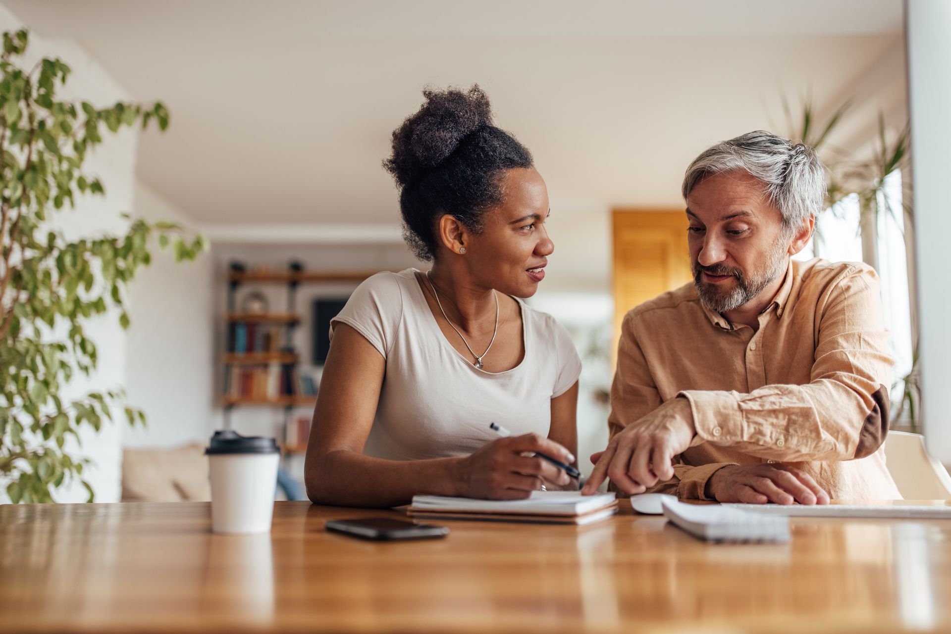 Two people reviewing documents at a table in a bright home office