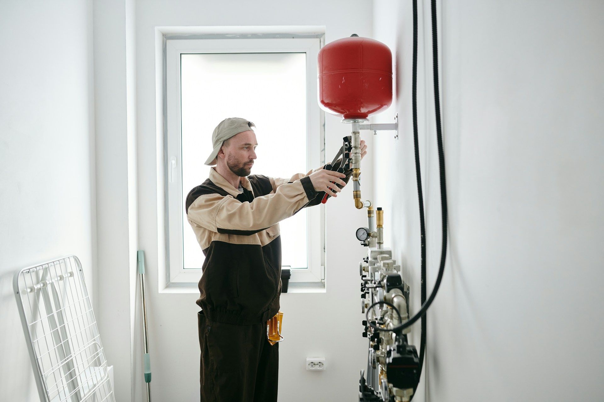 Technician inspecting a red pressure tank in a bright utility room