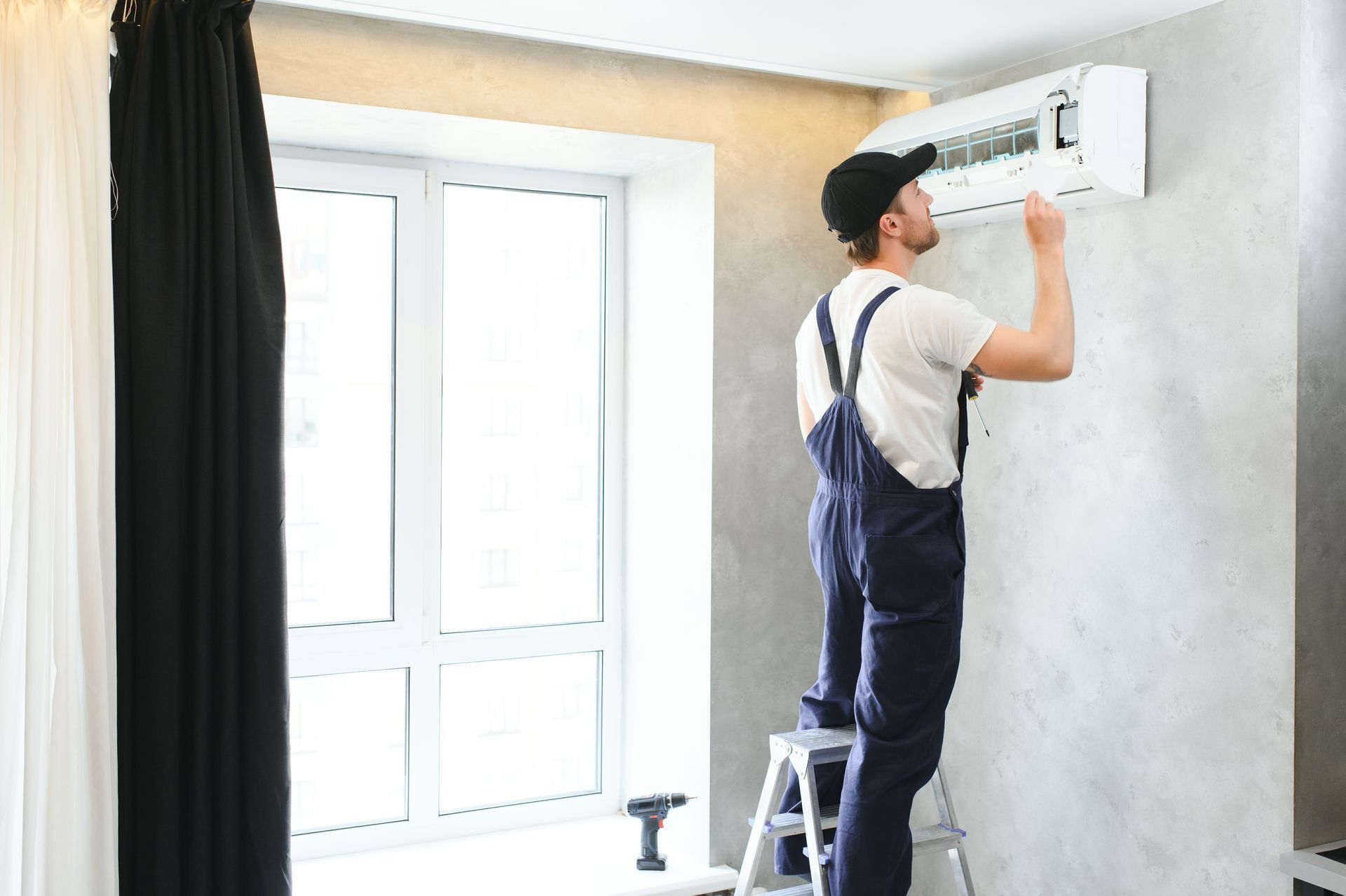 Technician installing a wall-mounted air conditioner in a bright room