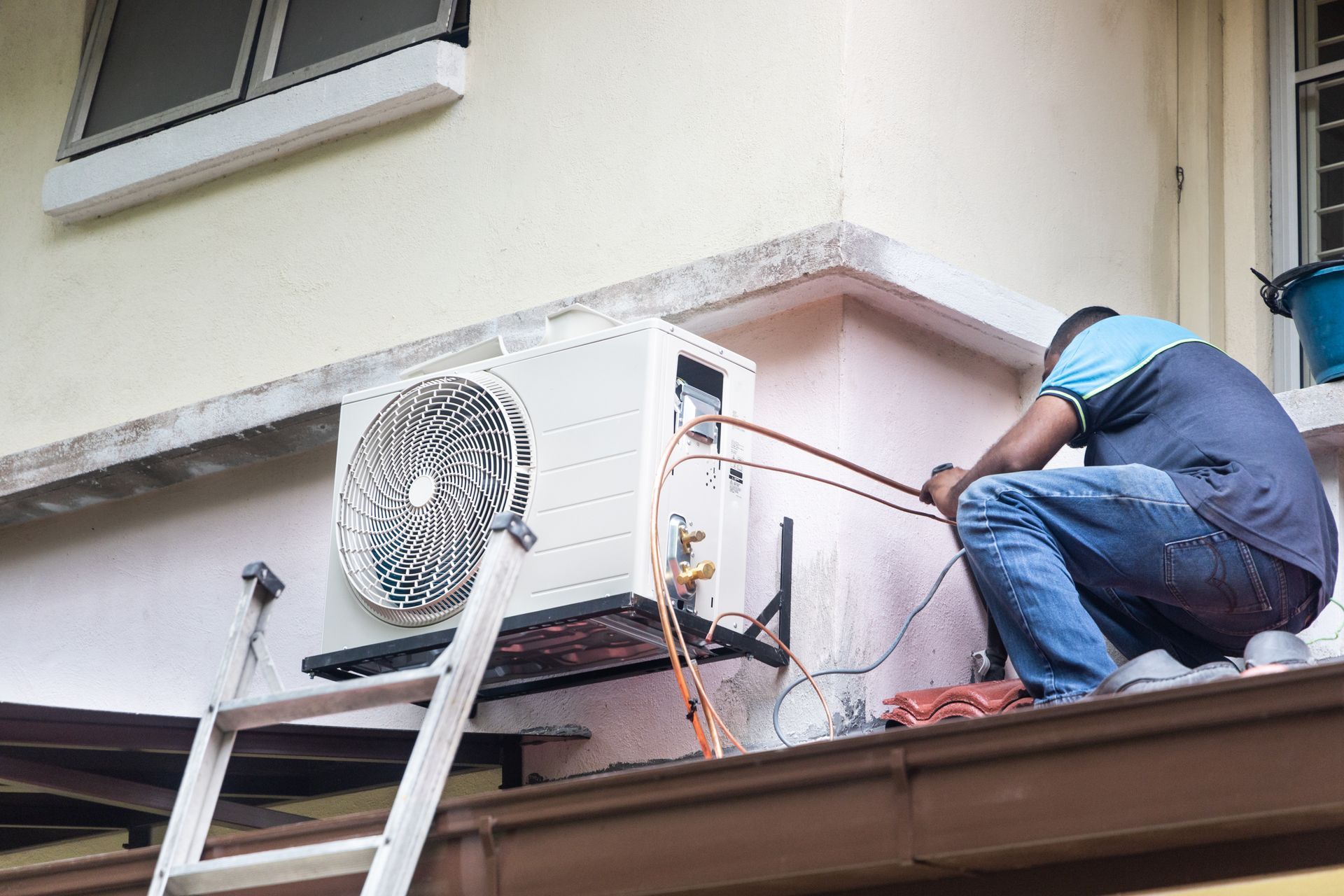 Technician repairing an outdoor air-conditioning unit on a building rooftop.