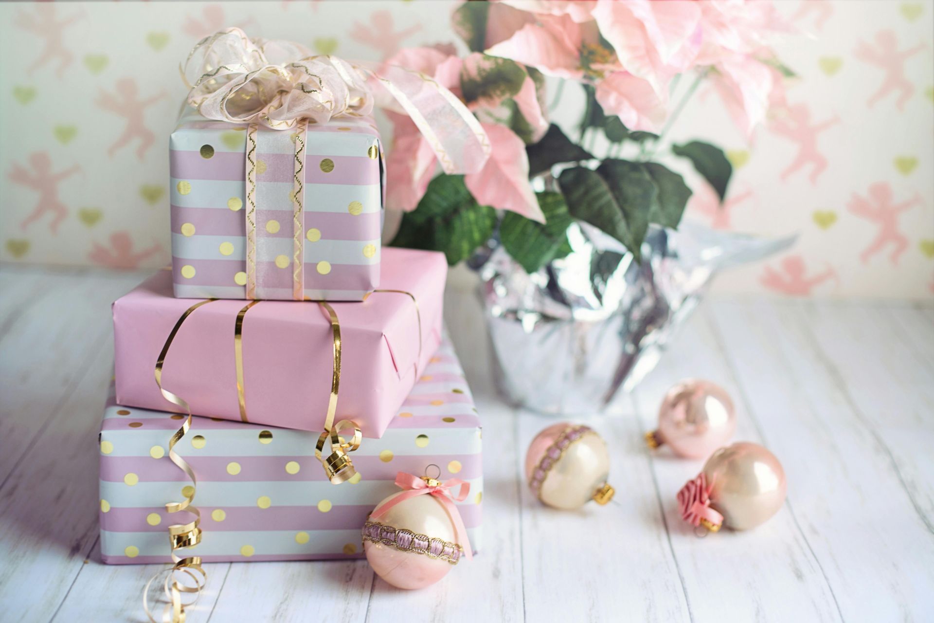 A stack of pink and white gifts sitting on top of each other on a wooden table.