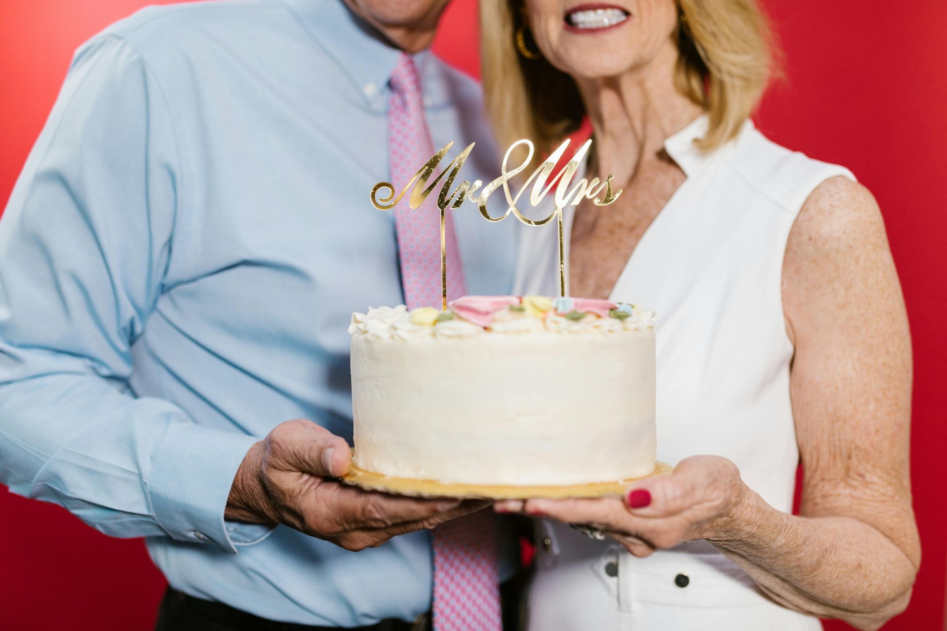 A man and a woman are holding a wedding cake.