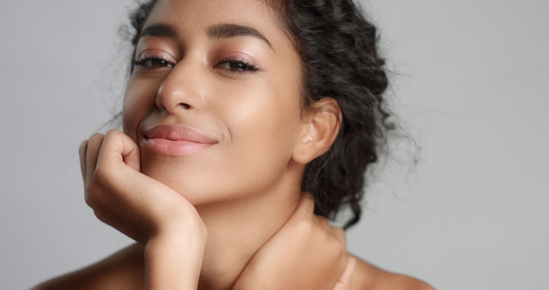 A close up of a woman 's face with her hand on her chin.