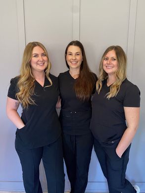 Three women in scrubs are posing for a picture together.