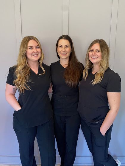 Three women in scrubs are posing for a picture together.