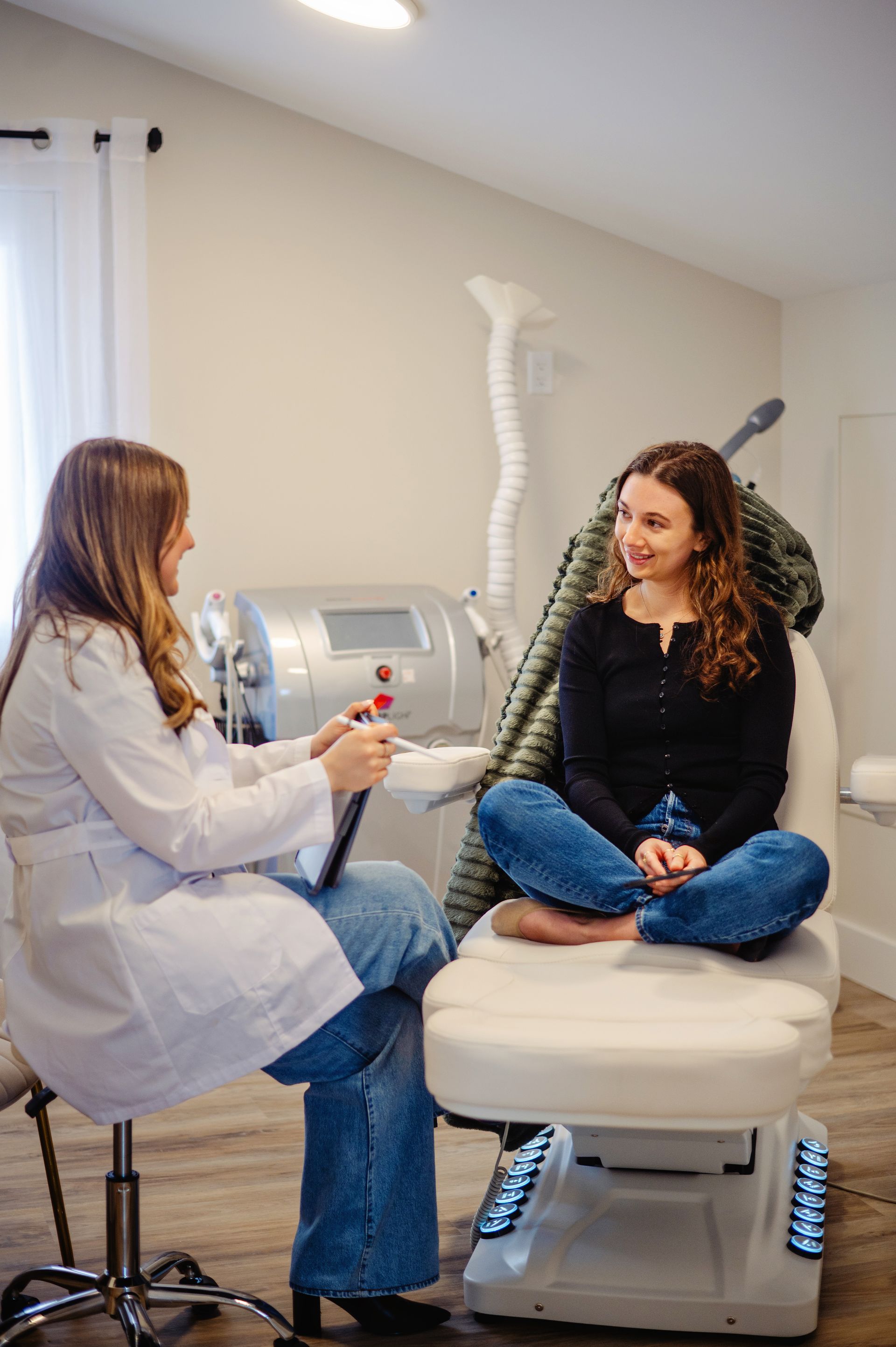 A woman is sitting at a table looking at her face in a mirror.