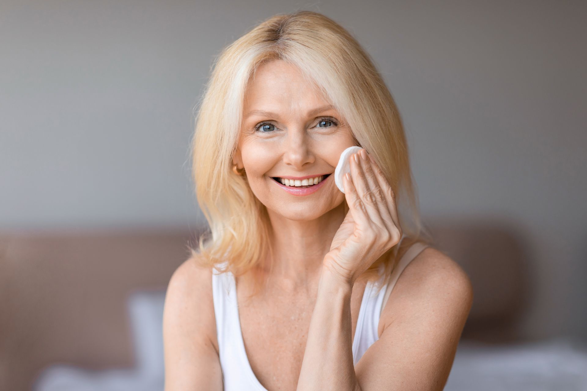 A woman is touching her face with her finger and smiling.