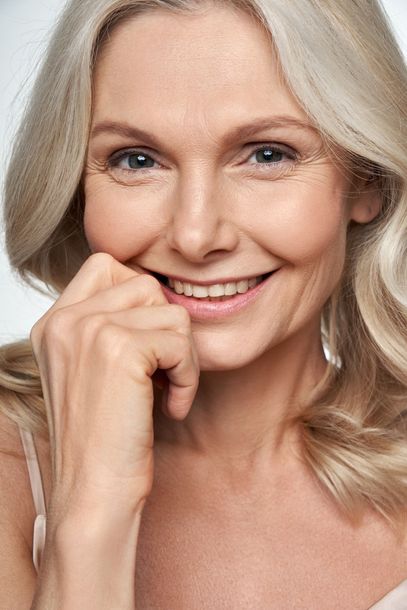 A close up of a woman smiling with her hand on her chin.