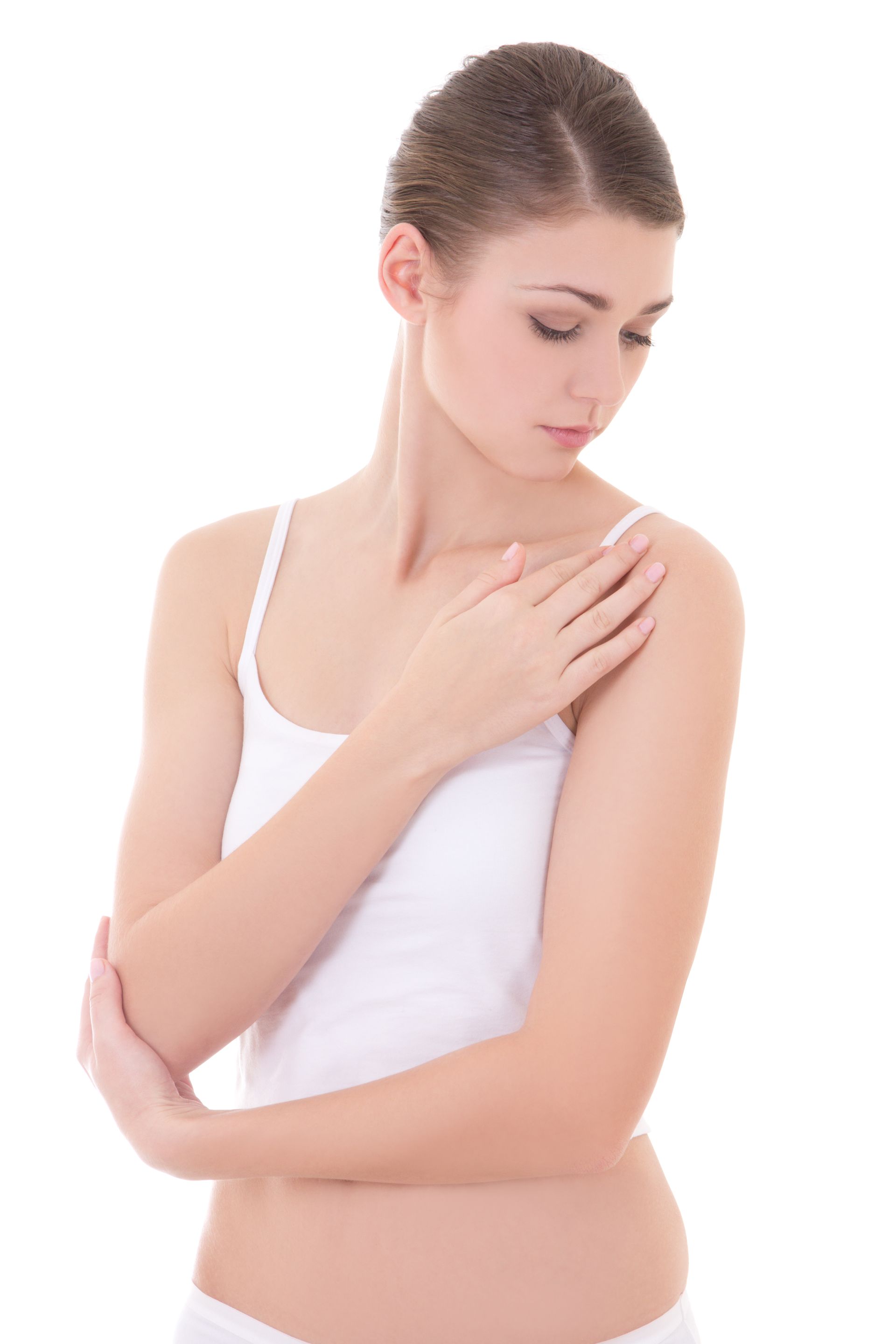 A woman in a white tank top is touching her shoulder.