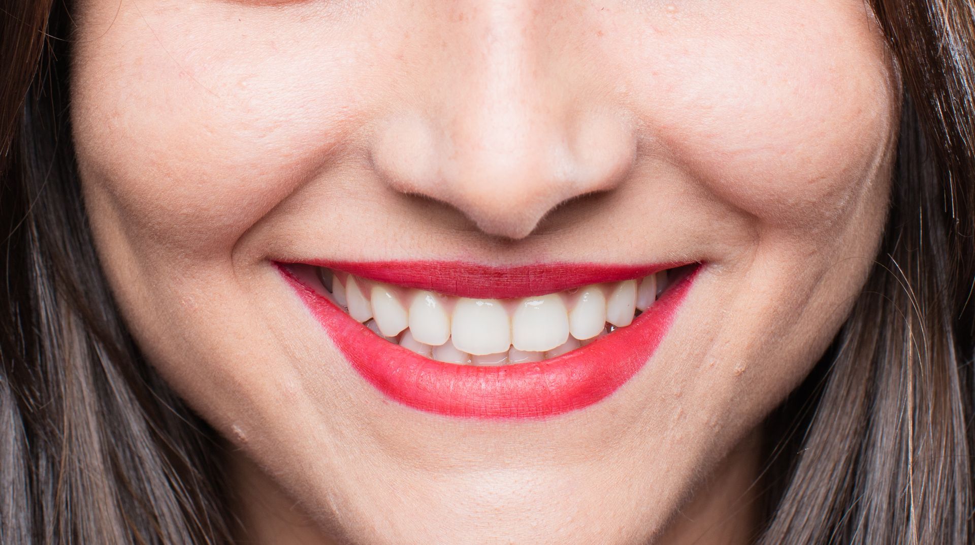 A close up of a woman 's smile with red lipstick.