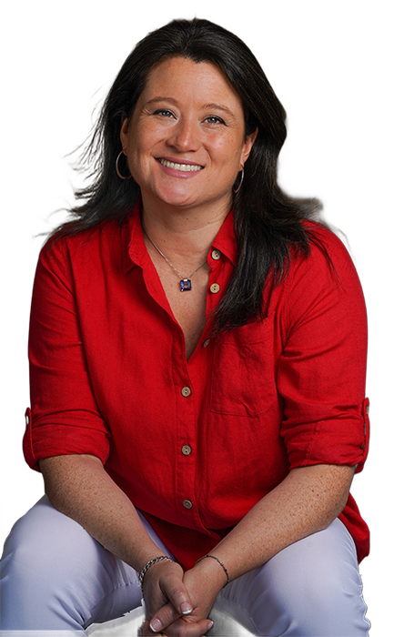 Una mujer con una camisa roja y pantalones blancos está sonriendo.