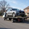 Gray Volvo SUV on a flatbed tow truck on a residential street.