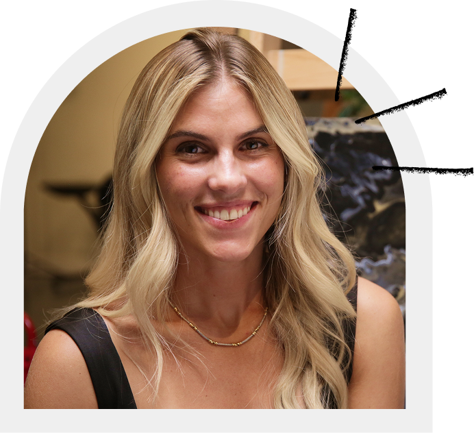 Woman with blonde hair smiling, wearing a black dress and gold necklace.