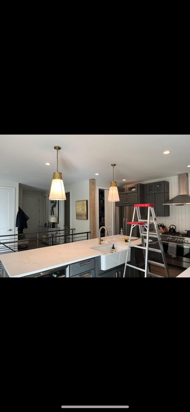 Kitchen with white countertops, gray cabinets, pendant lights, and a ladder.