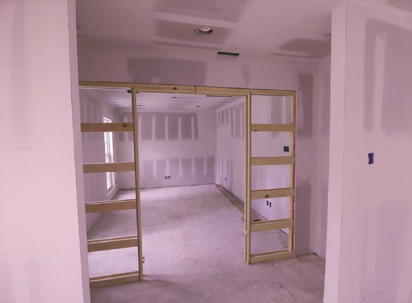 Partially finished room with built-in shelving and a doorway under construction
