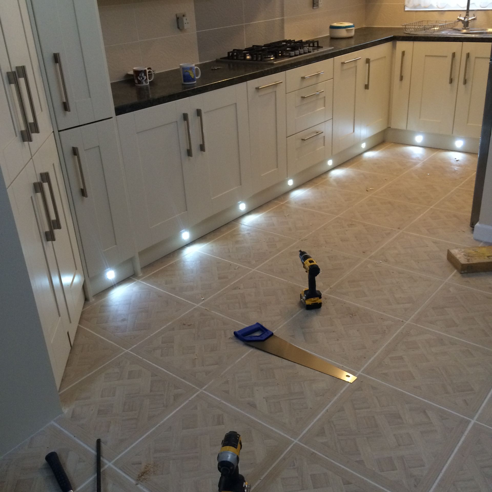 A kitchen with a drill and a saw on the floor